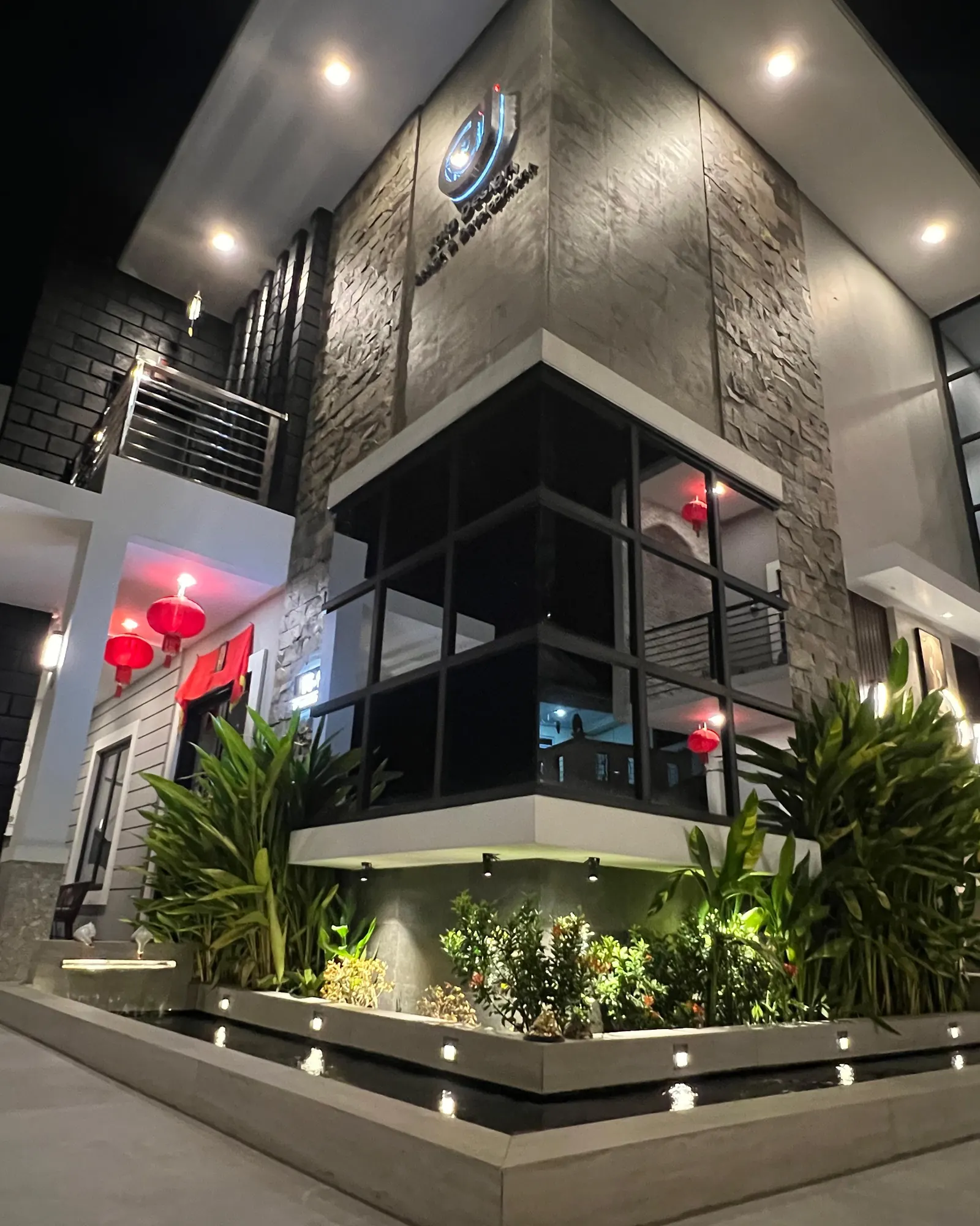 The Jaia Design showroom at night: a stone-clad corner building above a planted pond